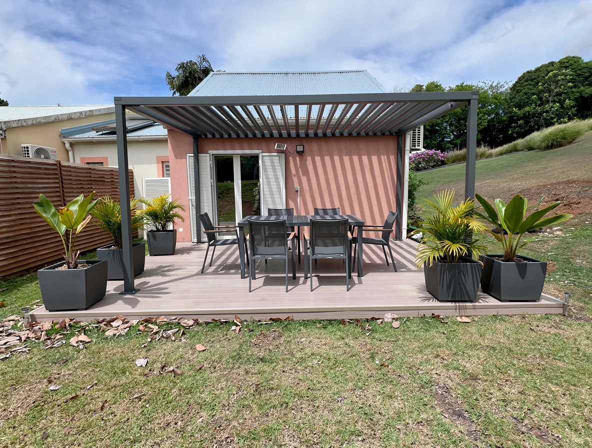 Pergola bioclimatique aluminium 4x3 anthracite abritant un salon d'extérieur au Lamentin, en Guadeloupe — réalisation GT MAT